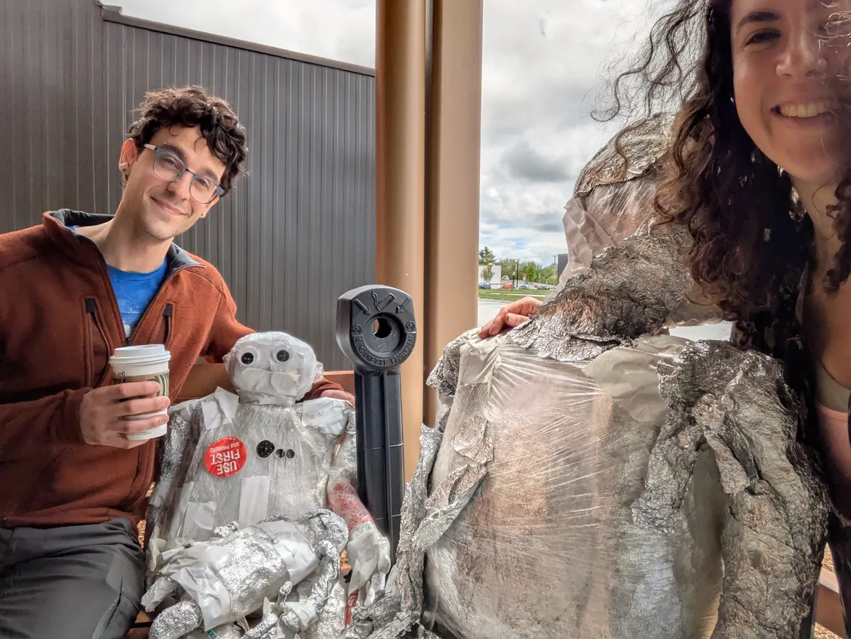 Grinning beside two foil sculptures wrapped for the trip